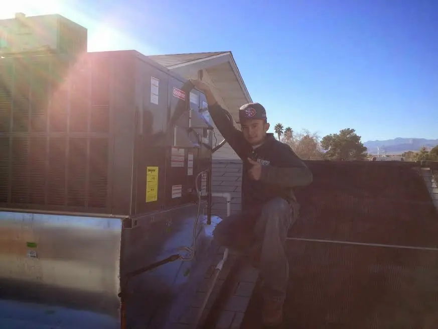 HVAC technician performing AC Tune-Up on a rooftop unit in Farr West